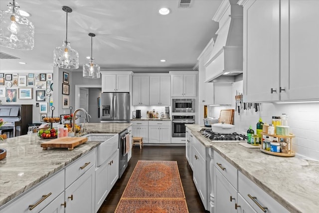 kitchen with a sink, custom range hood, white cabinetry, and stainless steel appliances