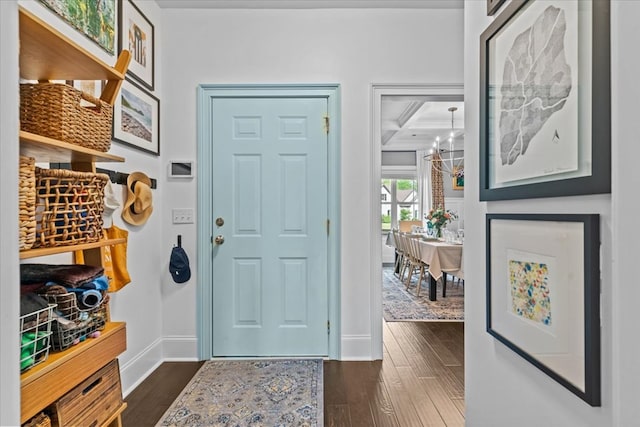 foyer with an inviting chandelier, beam ceiling, coffered ceiling, baseboards, and dark wood finished floors