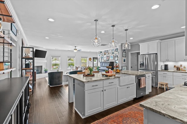 kitchen with white cabinetry, a sink, stainless steel appliances, open floor plan, and recessed lighting