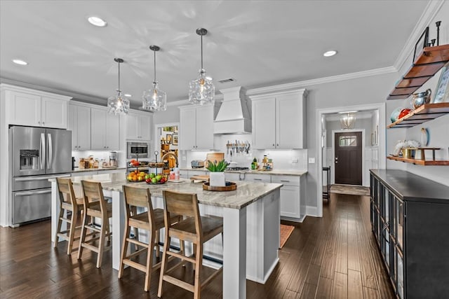 kitchen featuring white cabinets, appliances with stainless steel finishes, premium range hood, recessed lighting, and a center island with sink