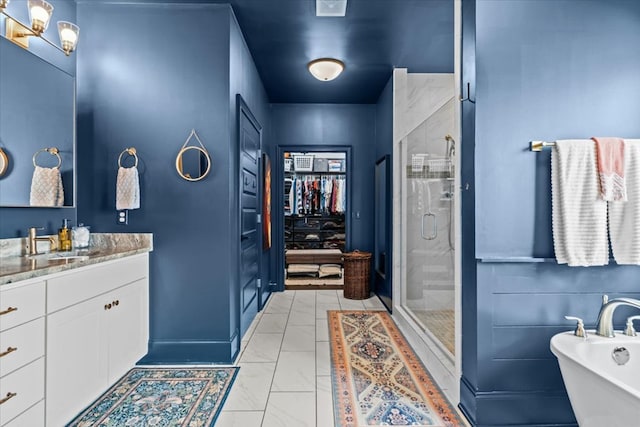 bathroom featuring vanity, a stall shower, marble finish floor, a walk in closet, and a soaking tub