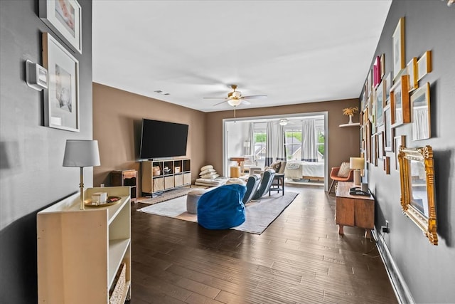 living room with baseboards, visible vents, ceiling fan, and dark wood-style flooring