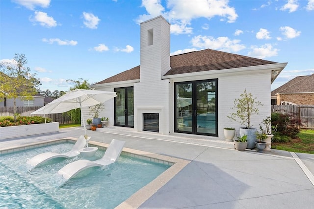 back of property featuring a fenced in pool, fence, a chimney, and a patio area