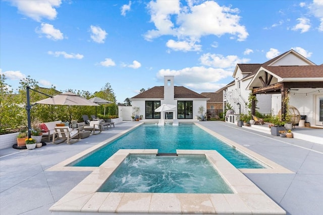 view of swimming pool with a patio area, an exterior structure, a pool with connected hot tub, and an outbuilding