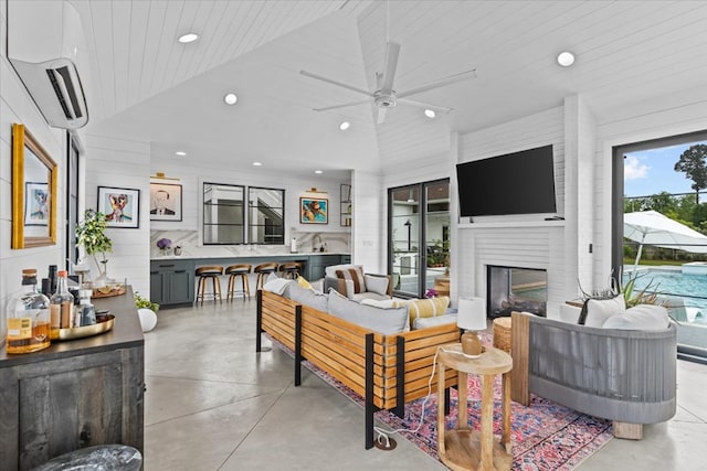 living room with recessed lighting, a wall unit AC, lofted ceiling, and concrete floors