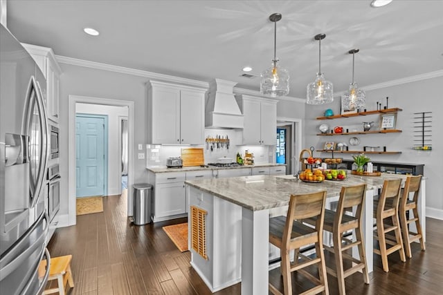 kitchen featuring a sink, stainless steel appliances, custom exhaust hood, white cabinetry, and ornamental molding