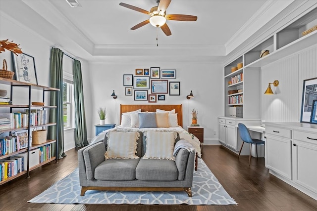 bedroom with built in desk, a tray ceiling, and dark wood-style floors
