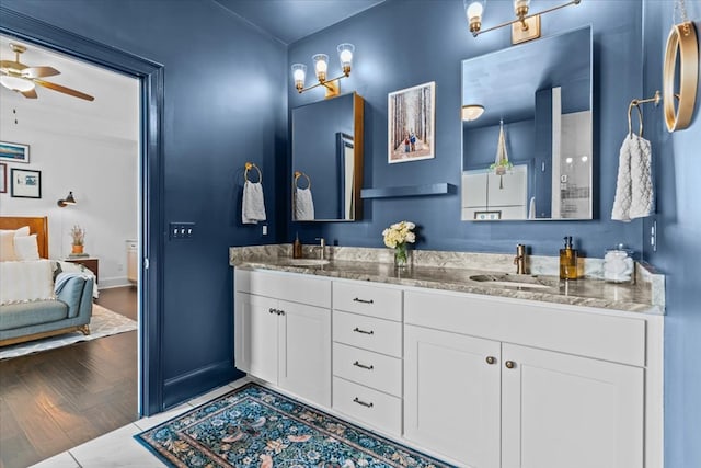 full bath with baseboards, a ceiling fan, double vanity, and a sink