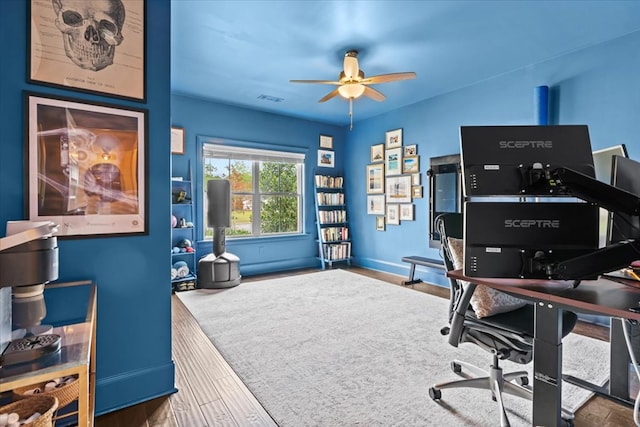 office space featuring wood finished floors, visible vents, a ceiling fan, and baseboards