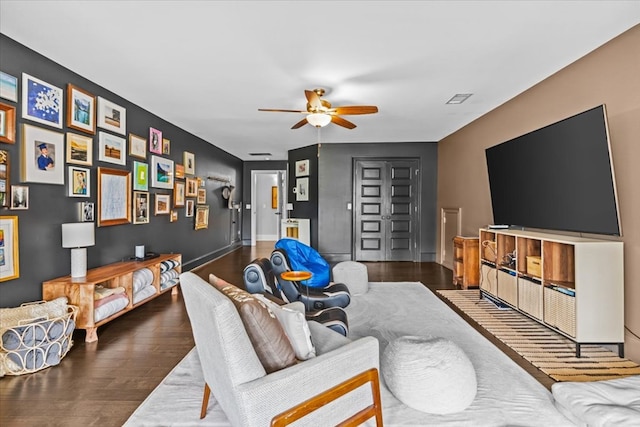 living room with wood finished floors, ceiling fan, visible vents, and baseboards