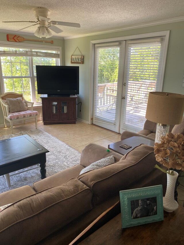 living room with ceiling fan, a textured ceiling, light tile patterned flooring, and crown molding