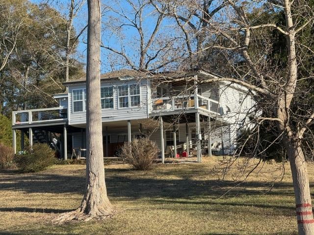 rear view of house featuring stairway, a lawn, and a deck