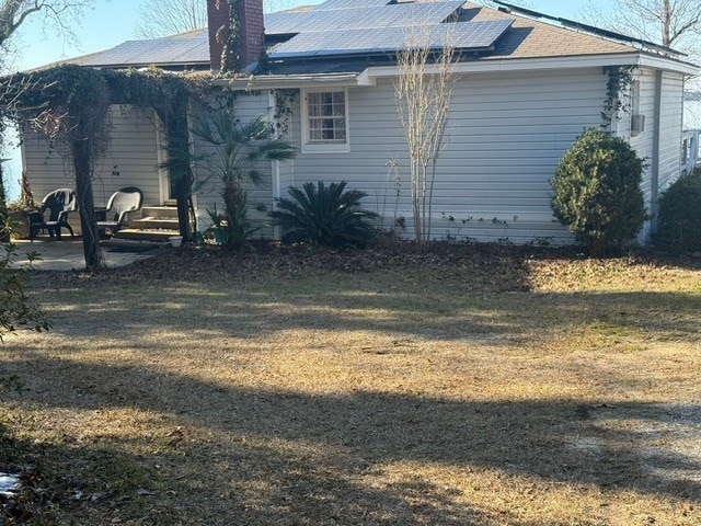 view of side of property featuring a lawn and solar panels