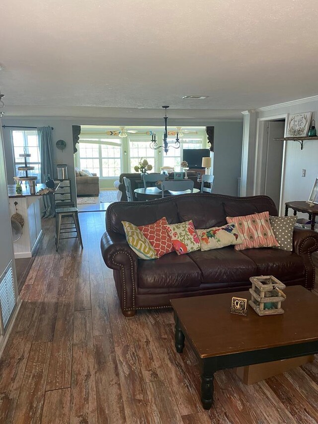 living room with crown molding, plenty of natural light, visible vents, and dark wood-style flooring