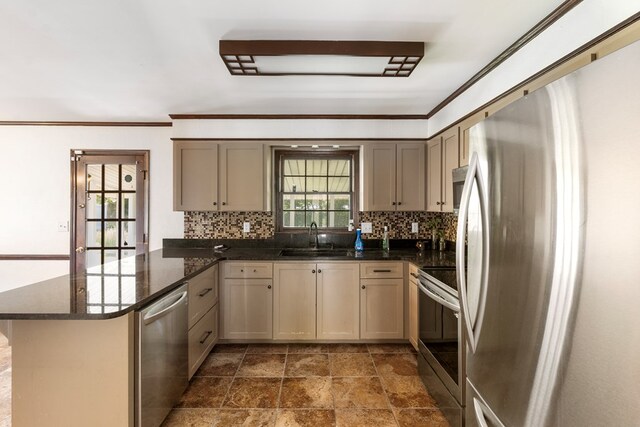 kitchen featuring sink, kitchen peninsula, dark stone countertops, decorative backsplash, and appliances with stainless steel finishes