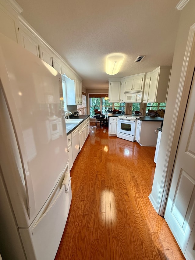 683 B Calhoun Dr, Abbeville, AL 36310 - kitchen with white appliances, dark countertops, wood finished floors, white cabinets, and backsplash
