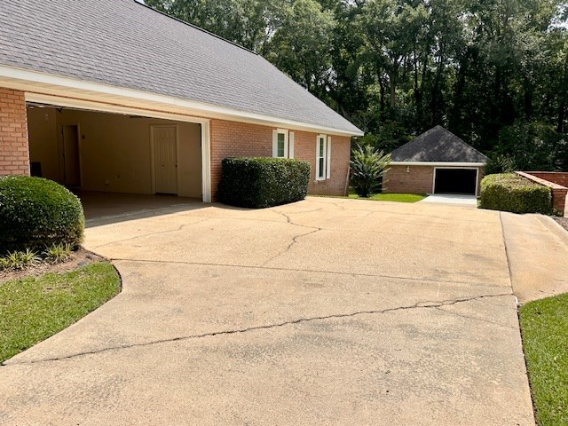 6 Woodmere Dr, Dothan, AL 36305 - view of side of property featuring brick siding, a garage, concrete driveway, roof with shingles, and an outdoor structure