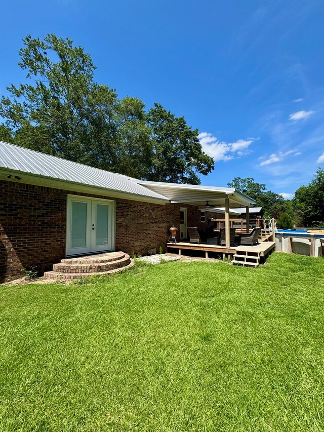 109 Pinehurst Dr, Ashford, AL 36312 - rear view of property featuring a wooden deck, an outdoor pool, french doors, a lawn, and brick siding