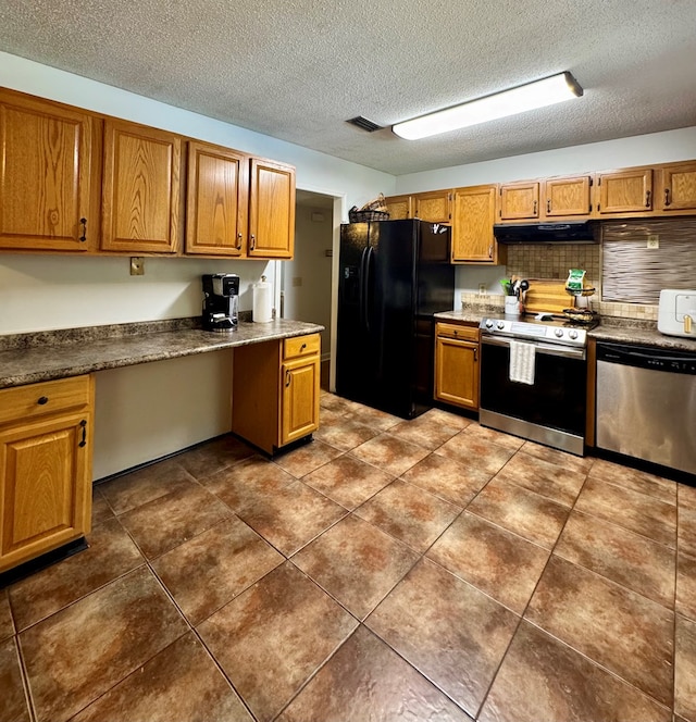109 Pinehurst Dr, Ashford, AL 36312 - kitchen featuring stainless steel appliances, under cabinet range hood, brown cabinets, built in study area, and a textured ceiling