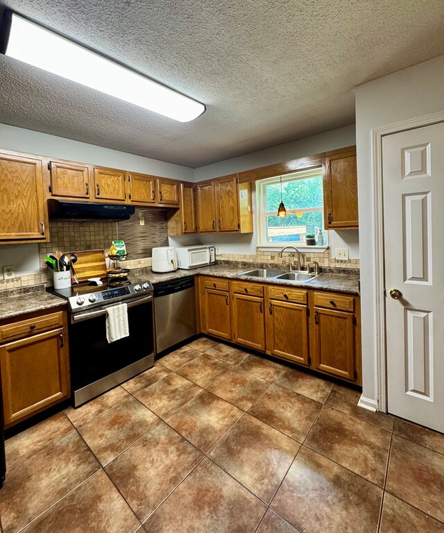 109 Pinehurst Dr, Ashford, AL 36312 - kitchen with stainless steel appliances, dark countertops, brown cabinetry, decorative backsplash, and a textured ceiling