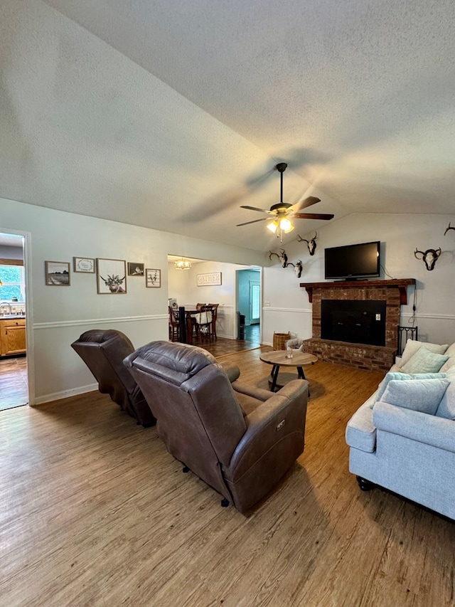 109 Pinehurst Dr, Ashford, AL 36312 - living area with a textured ceiling, ceiling fan, wood finished floors, lofted ceiling, and a brick fireplace