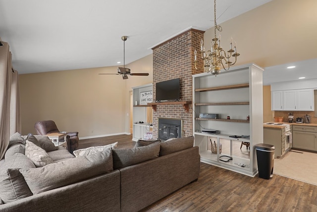 living room featuring wood-type flooring, lofted ceiling, ceiling fan with notable chandelier, and a fireplace