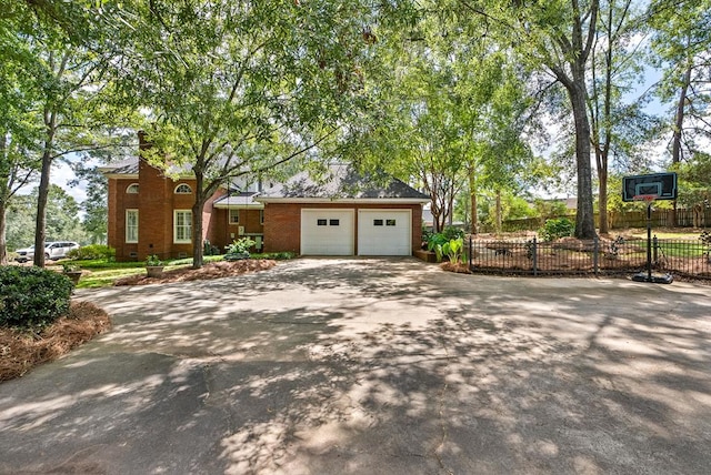 view of front of home featuring a garage, driveway, brick siding, and fence