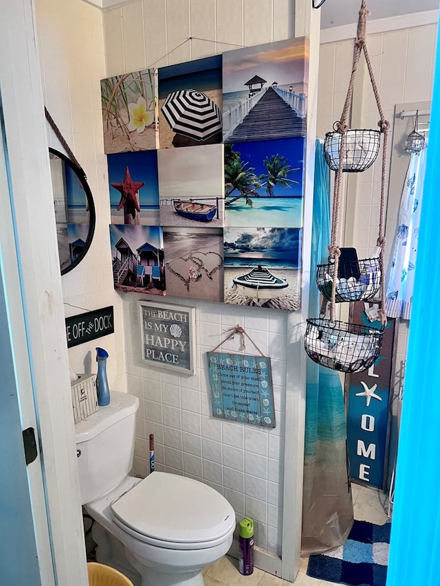 bathroom featuring toilet and tile walls