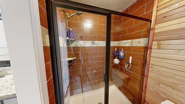 bathroom featuring a shower with shower door and a textured ceiling