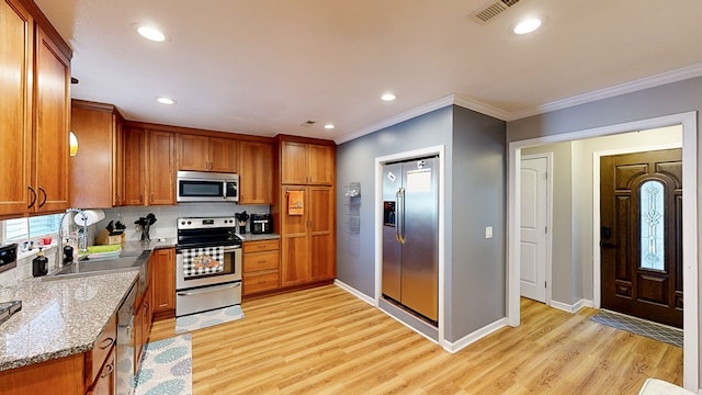 kitchen featuring light stone countertops, crown molding, light hardwood / wood-style floors, and appliances with stainless steel finishes