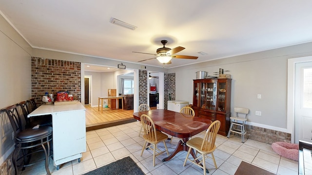 dining space with light hardwood / wood-style floors, ceiling fan, crown molding, and brick wall