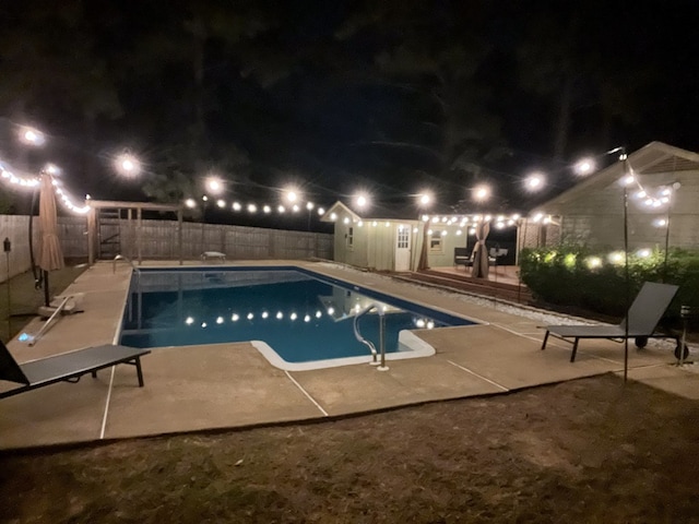 pool at night featuring a patio