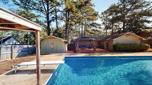 view of swimming pool with a gazebo, a wooden deck, a diving board, and a storage shed