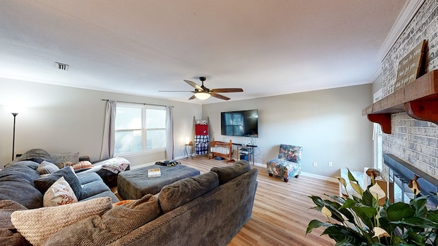 living room with ceiling fan, a fireplace, light hardwood / wood-style floors, and ornamental molding