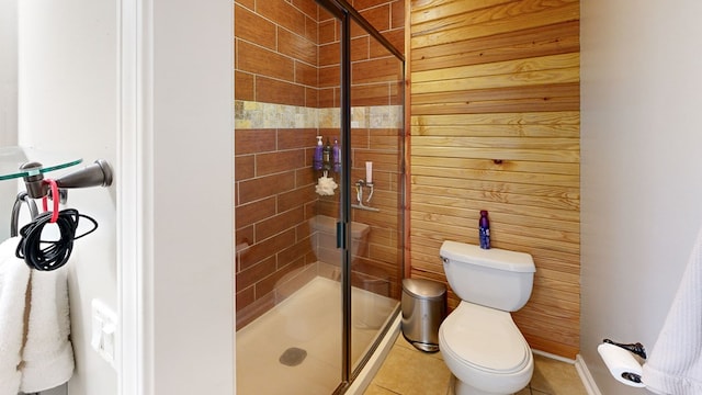 bathroom featuring tile patterned floors, wood walls, toilet, and walk in shower