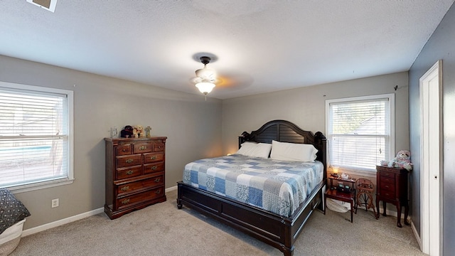 carpeted bedroom with ceiling fan and a textured ceiling