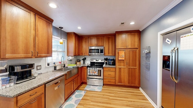 kitchen featuring sink, stainless steel appliances, ornamental molding, pendant lighting, and light wood-type flooring