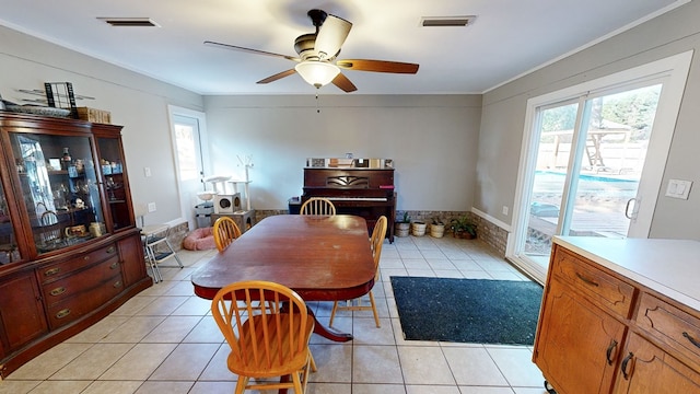 tiled dining room with ceiling fan and ornamental molding