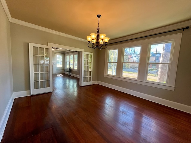 unfurnished dining area featuring a chandelier, dark wood-type flooring, a wealth of natural light, and ornamental molding