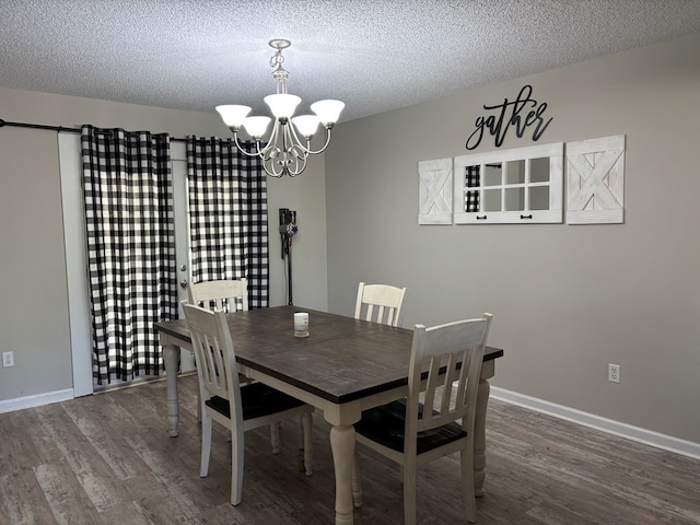 dining space featuring baseboards, wood finished floors, a chandelier, and a textured ceiling