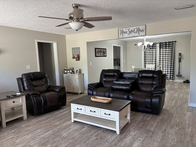 living room with baseboards, wood finished floors, a textured ceiling, and ceiling fan with notable chandelier