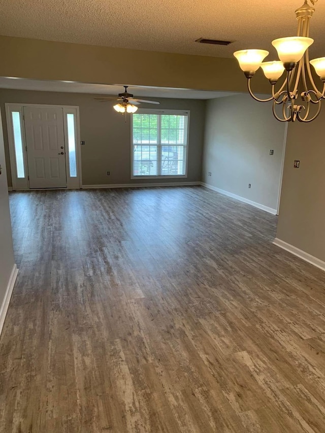 unfurnished living room with wood finished floors, a textured ceiling, ceiling fan with notable chandelier, baseboards, and visible vents
