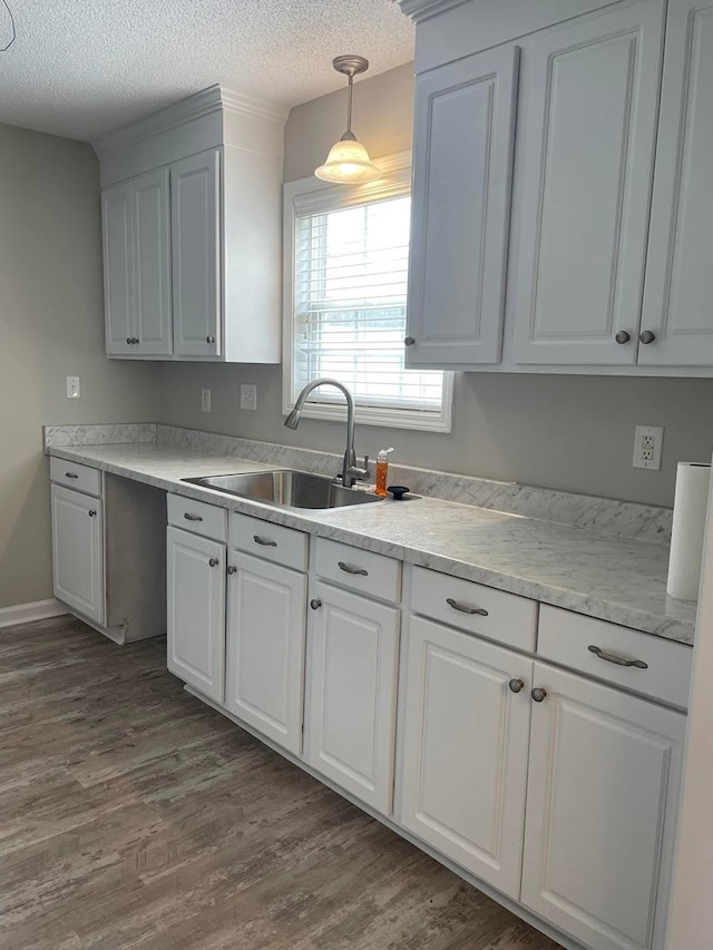kitchen with light countertops, a textured ceiling, dark wood-style floors, and a sink