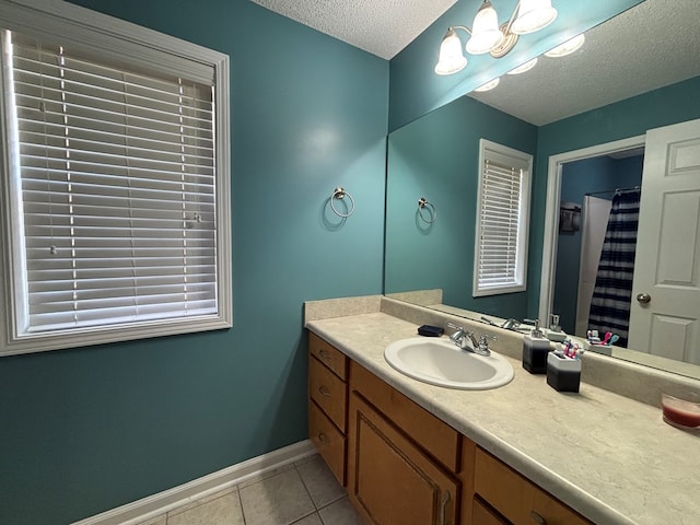bathroom featuring baseboards, vanity, tile patterned floors, and a textured ceiling