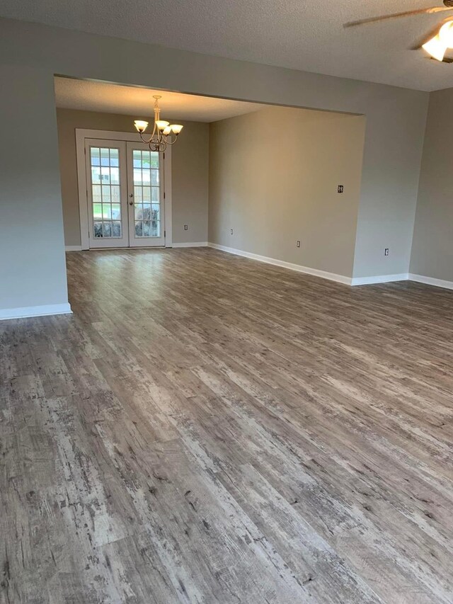 spare room featuring baseboards, a notable chandelier, wood finished floors, and a textured ceiling