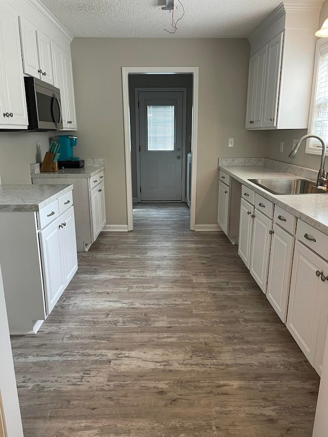 kitchen with stainless steel microwave, a wealth of natural light, a sink, and light countertops