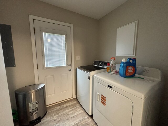 washroom with light wood finished floors, electric panel, washer and dryer, and laundry area
