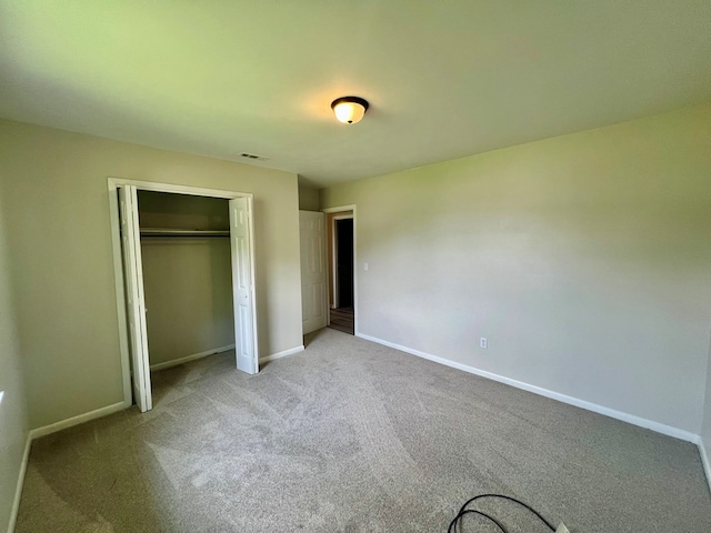 unfurnished bedroom with light colored carpet and a closet