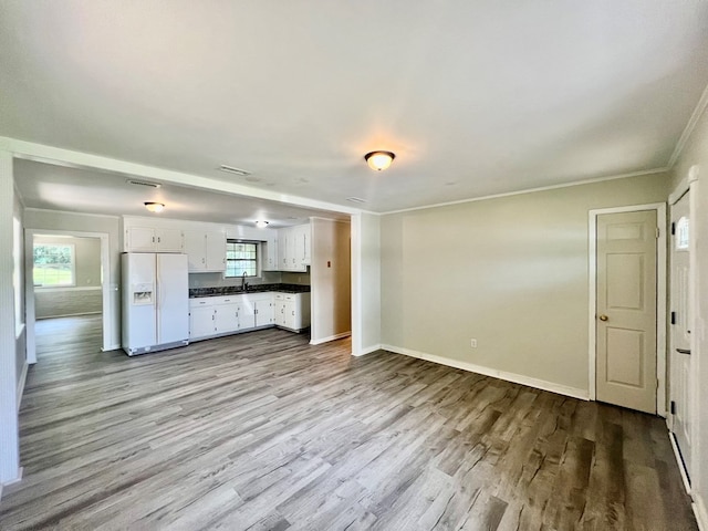 unfurnished living room featuring light wood-type flooring, ornamental molding, and sink