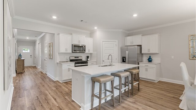 110 Creekridge St, Headland, AL 36345 - kitchen with appliances with stainless steel finishes, a sink, a breakfast bar area, light wood-style floors, and light countertops
